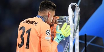 Ederson beijando a taça da Champions depois de ser campeão pelo City | Foto: Michael Regan | UEFA/UEFA - Getty Images